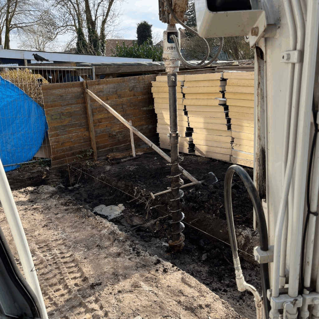 Minikraan & -shovel: Grondboor minikraan. T.b.v. het boren van gaten voor bijv.: Schuttingpalen, drainage of funderingspalen. De laatste, in combinatie met de mixbak, zorgt voor het vlot storten van funderingspalen, zonder zware fysieke inspanning.